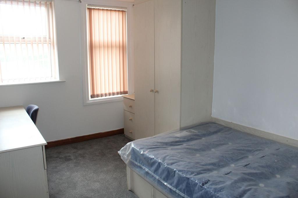 A simple, basic bedroom featuring a window with...
