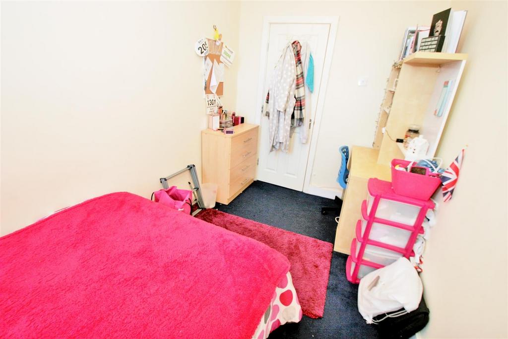 A cozy student bedroom featuring a vibrant pink...