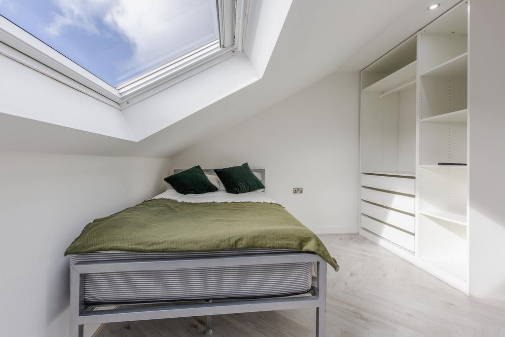 A bright, minimalist bedroom with a skylight th...