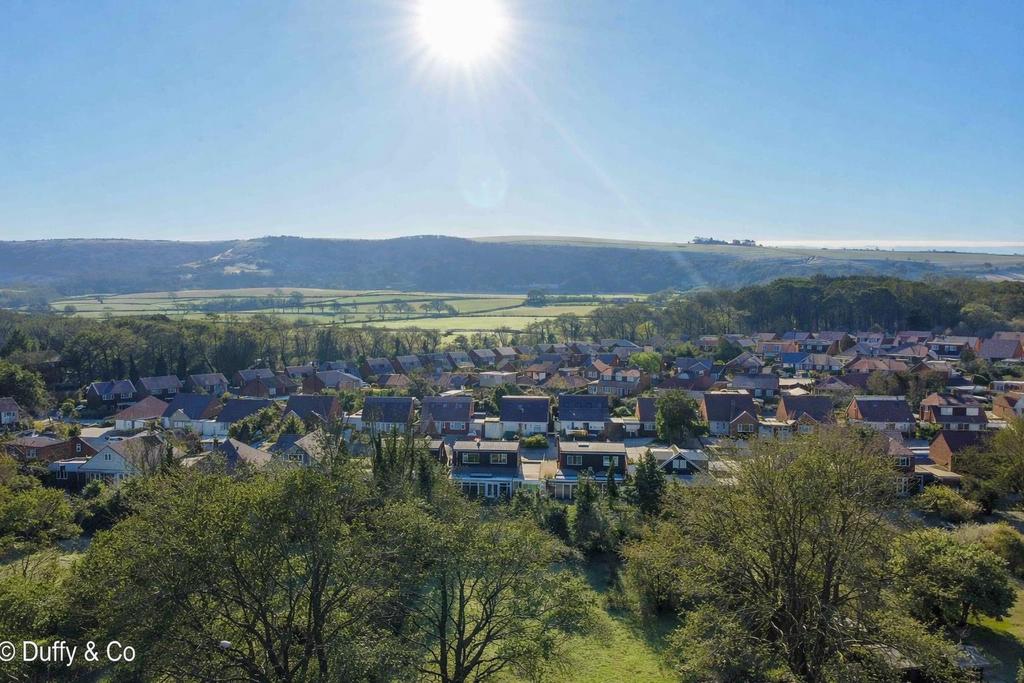 Sunlit village with rolling hills.png