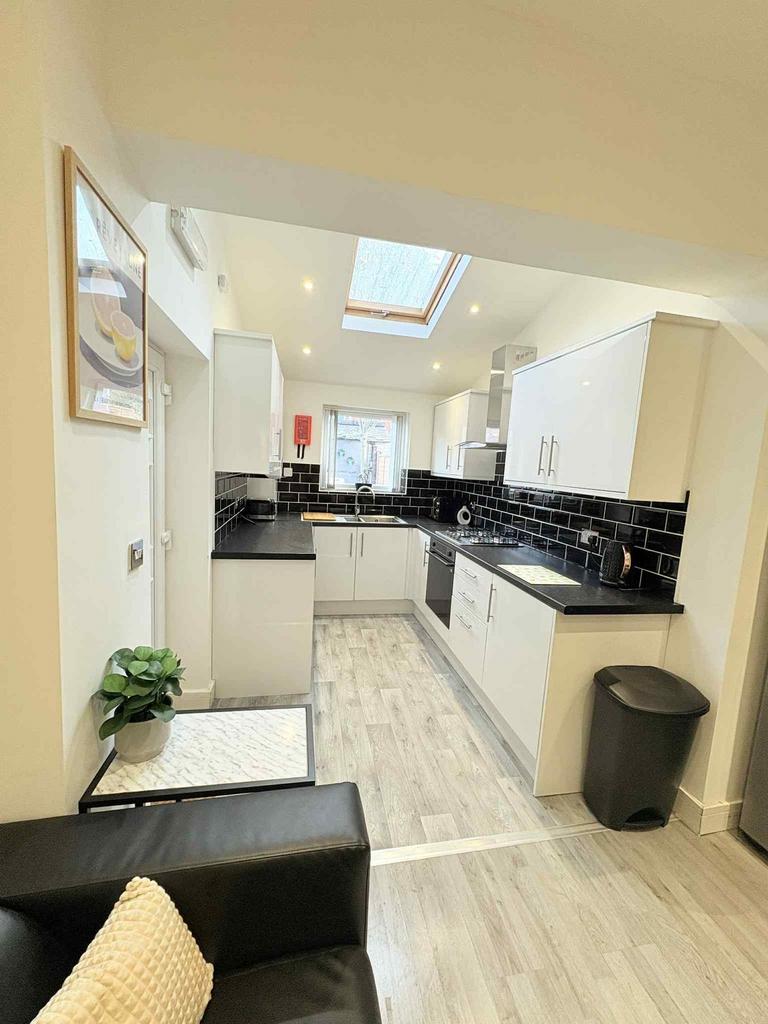 Bright modern kitchen with white cabinets, blac...