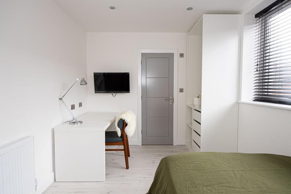 A clean and bright bedroom featuring a comforta...