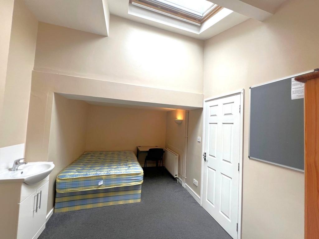 Bright attic-style single bedroom with a skylig...
