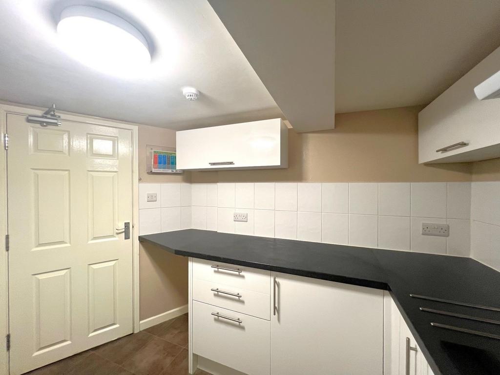 Neat modern kitchenette with white shaker cabin...