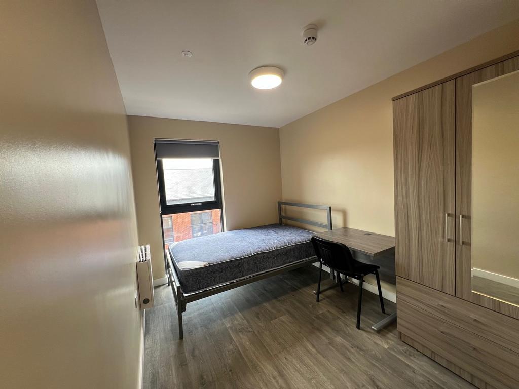 A cozy student bedroom featuring a large window...