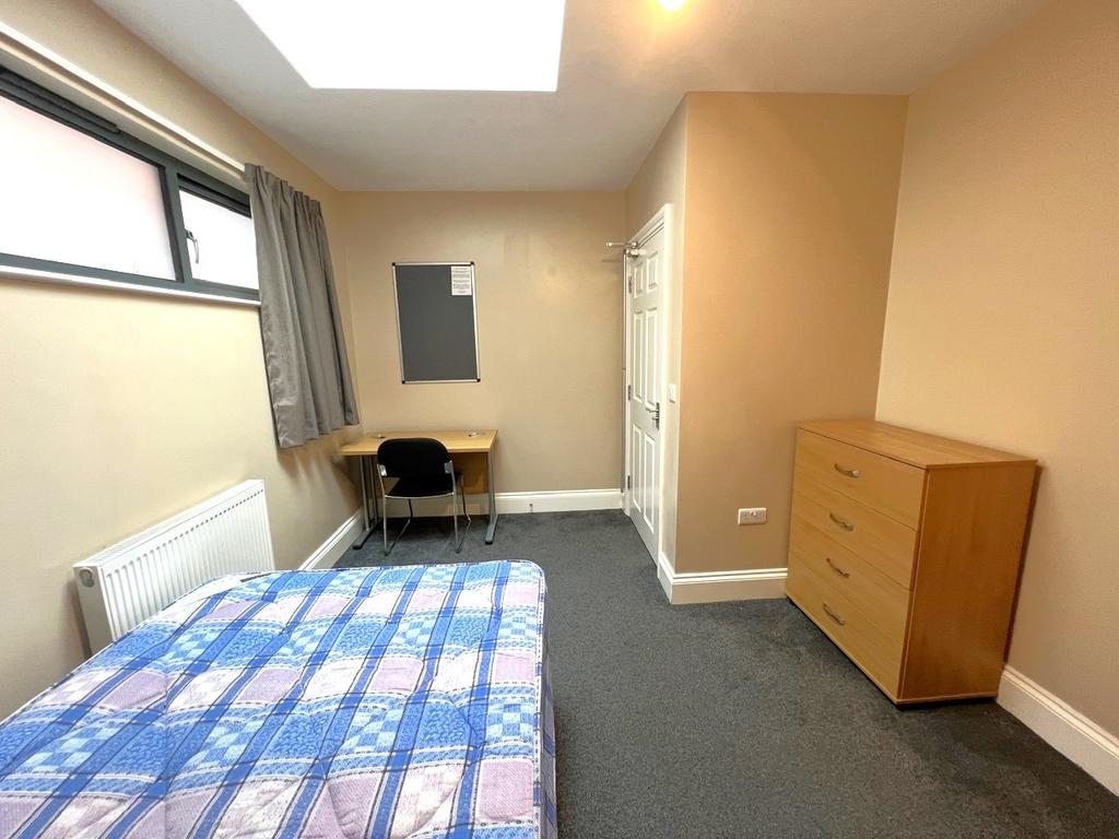 Bright, simply furnished bedroom with a double ...