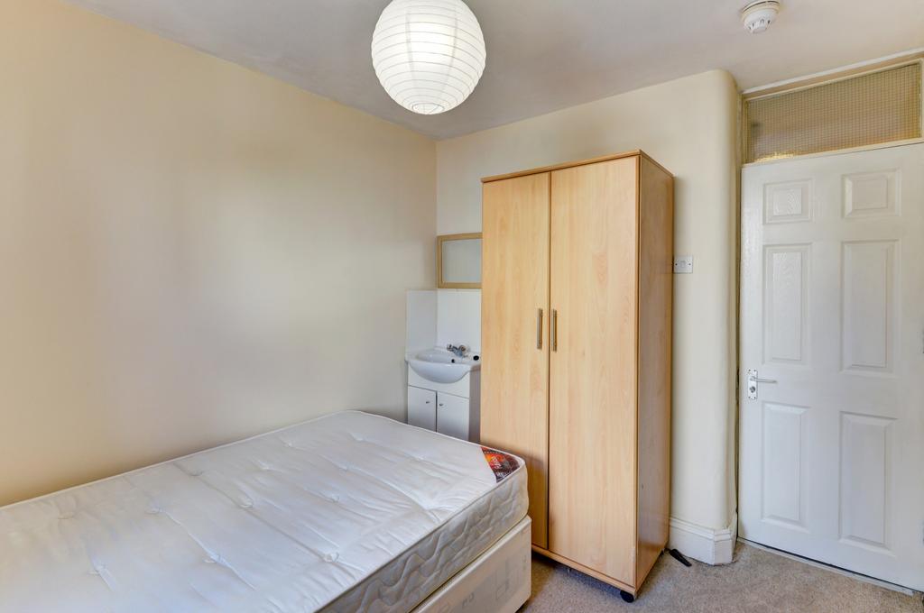 A cozy bedroom featuring a single bed, a wardro...