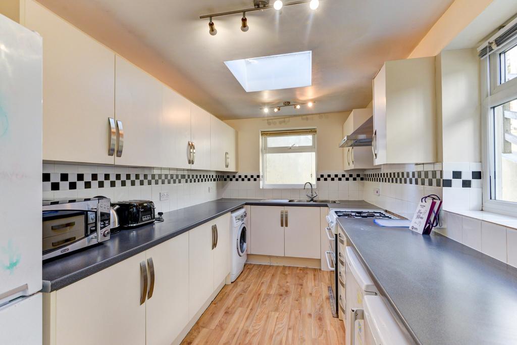Bright, modern galley kitchen with white fitted...