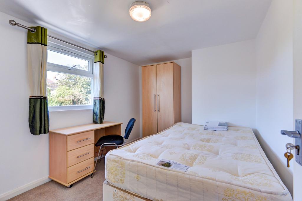 A bright, neatly kept bedroom featuring a comfo...