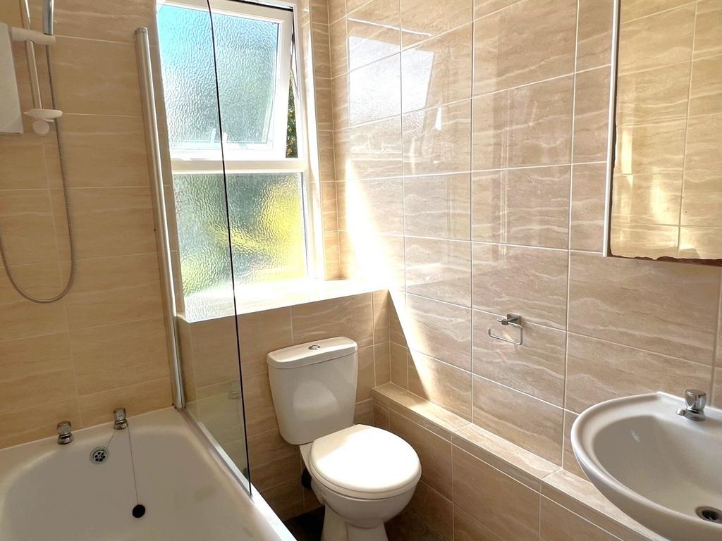 Bright, modern bathroom with tiled walls, a com...