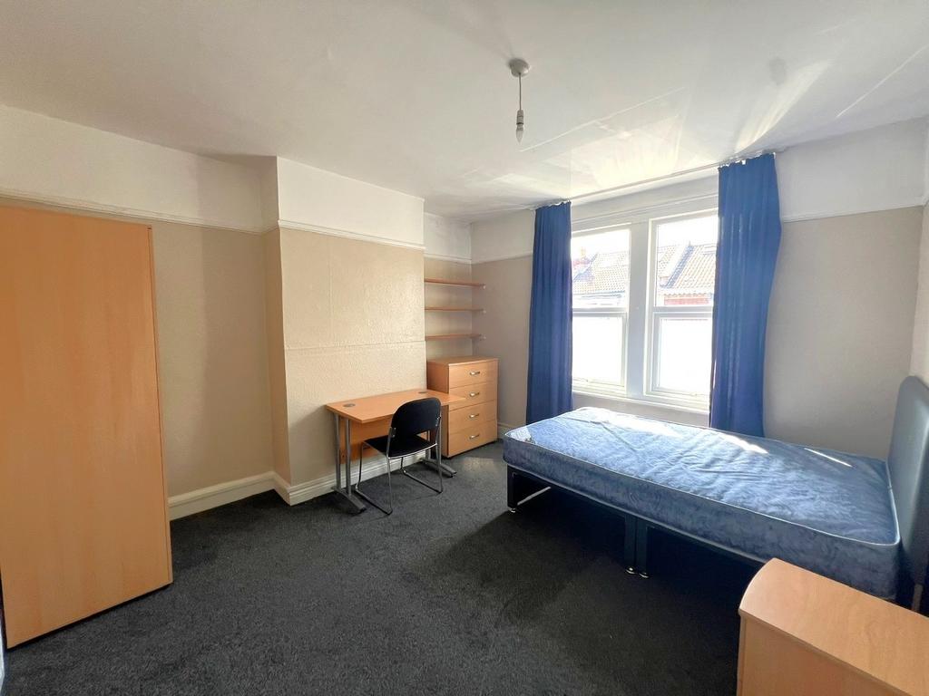 A cozy student bedroom featuring a bed by the w...