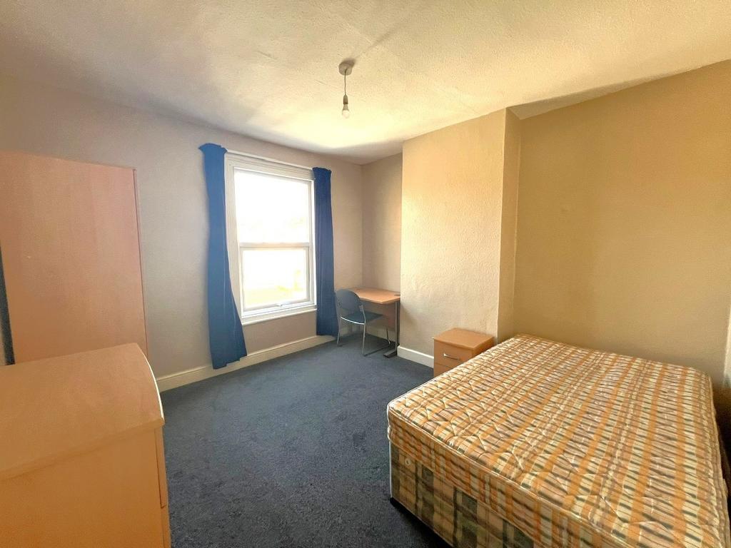 A modest single bedroom with a window letting i...