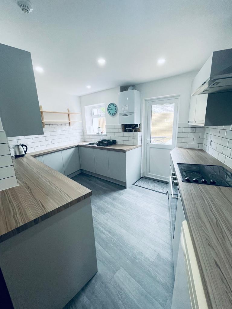 Bright modern kitchen with L-shaped worktops, w...