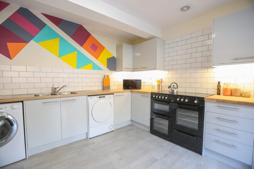 Modern kitchen with stylish white cabinetry, a ...