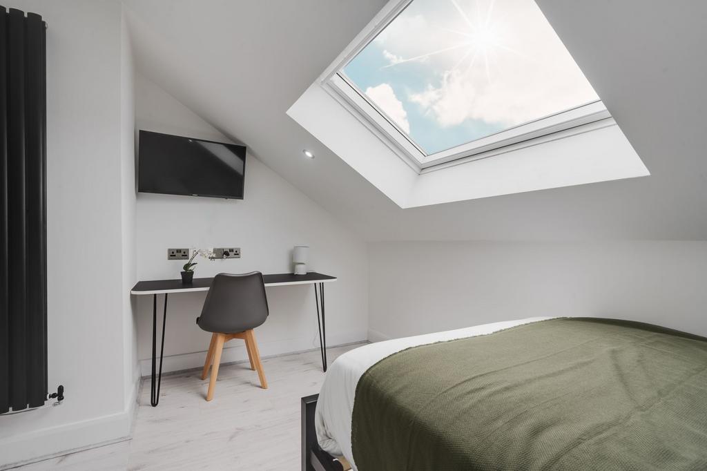 Bright and airy bedroom featuring a large skyli...