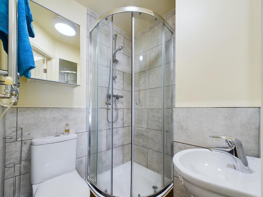 Bright, modern bathroom with a curved glass sho...