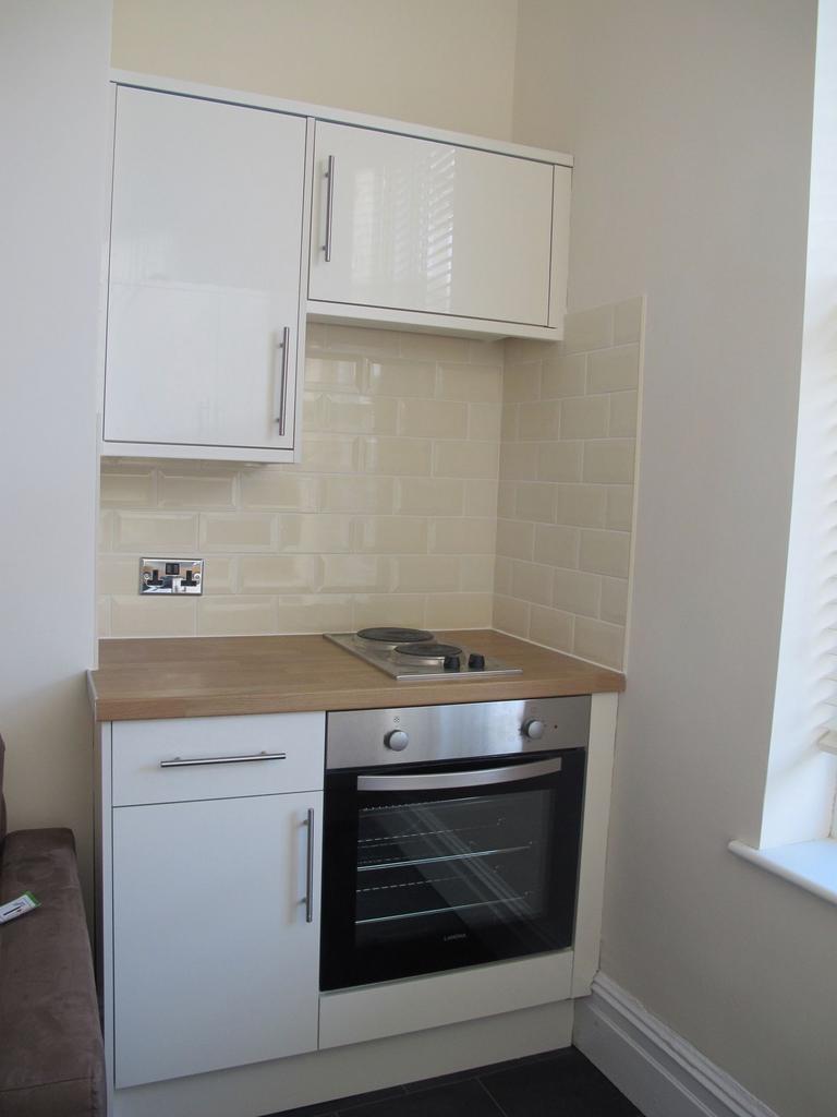 Modern compact kitchenette with white cabinetry...
