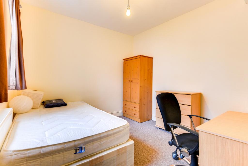 A comfortable single bedroom featuring a bed, d...
