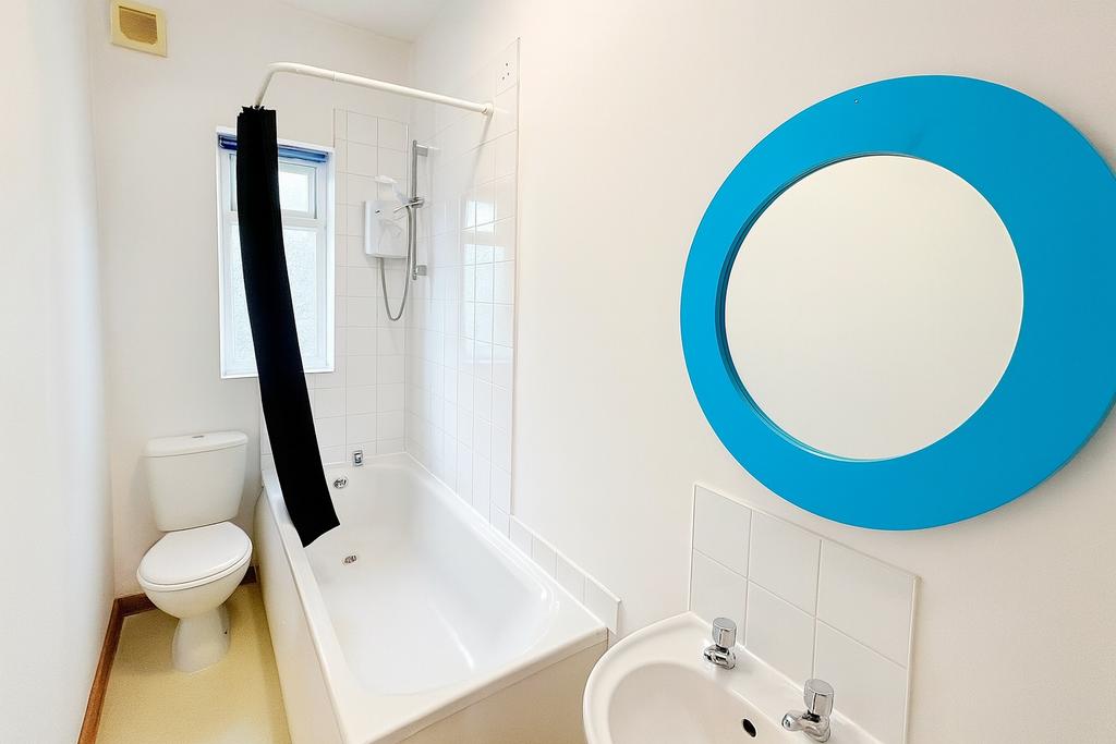 Bright, clean bathroom with a white bath and sh...