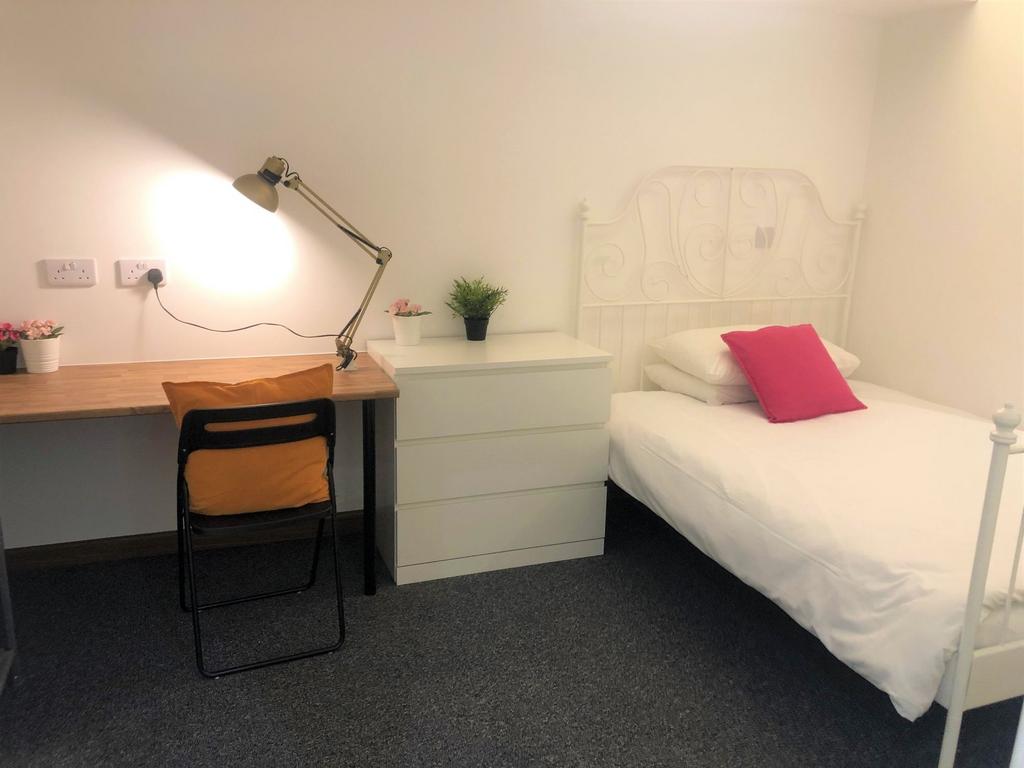A neat and cozy single bedroom featuring a whit...