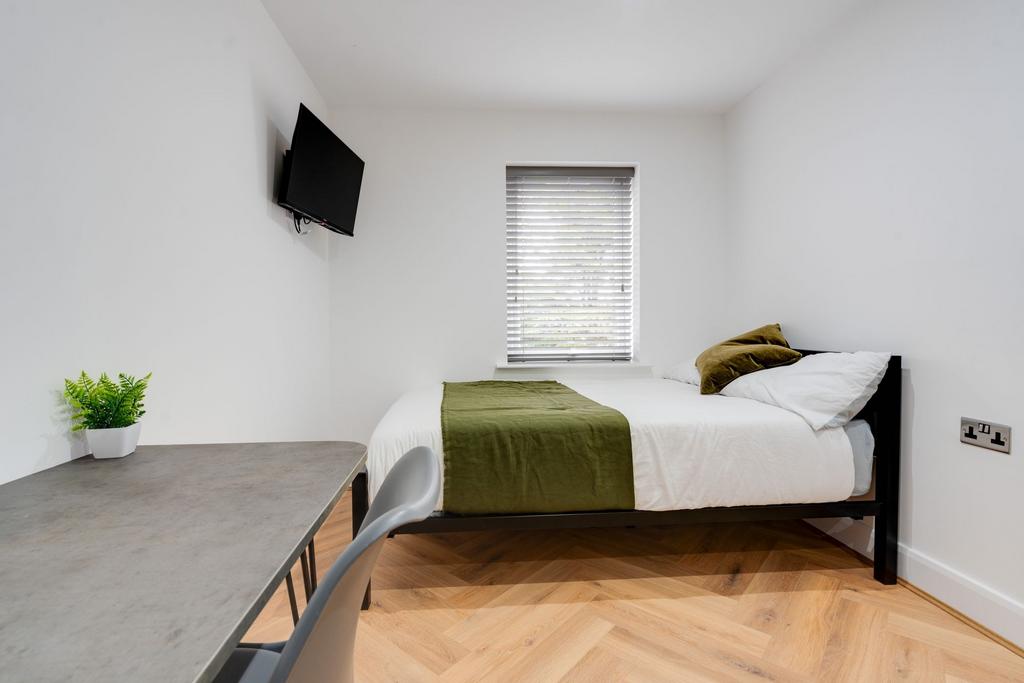 A bright, clean single bedroom featuring a comf...