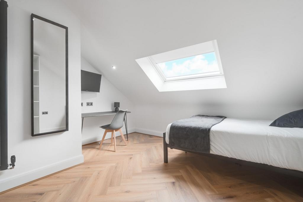 A bright and modern double bedroom with a skyli...