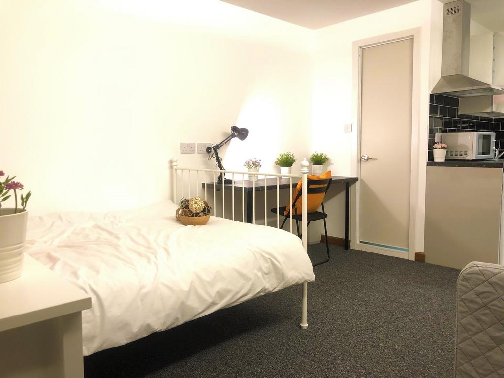 A bright, cozy single bedroom featuring a neat ...