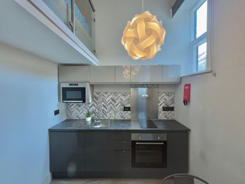 Modern compact kitchen with sleek dark lower ca...
