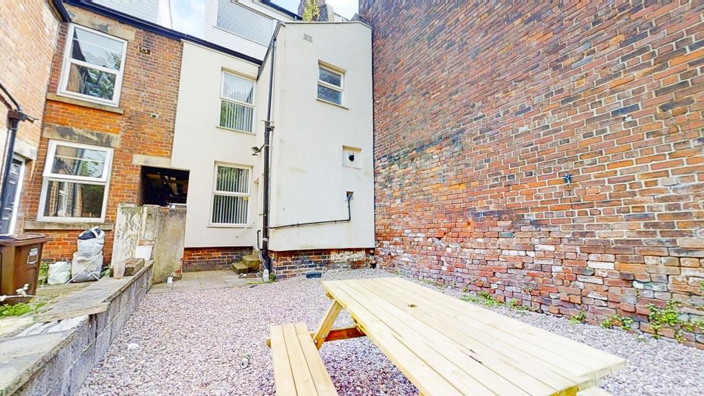 Walled courtyard with a picnic bench on gravel,...