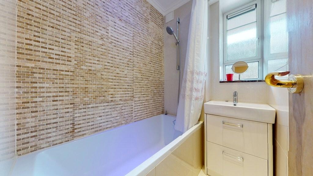 Modern bathroom with a white bathtub, tiled mos...