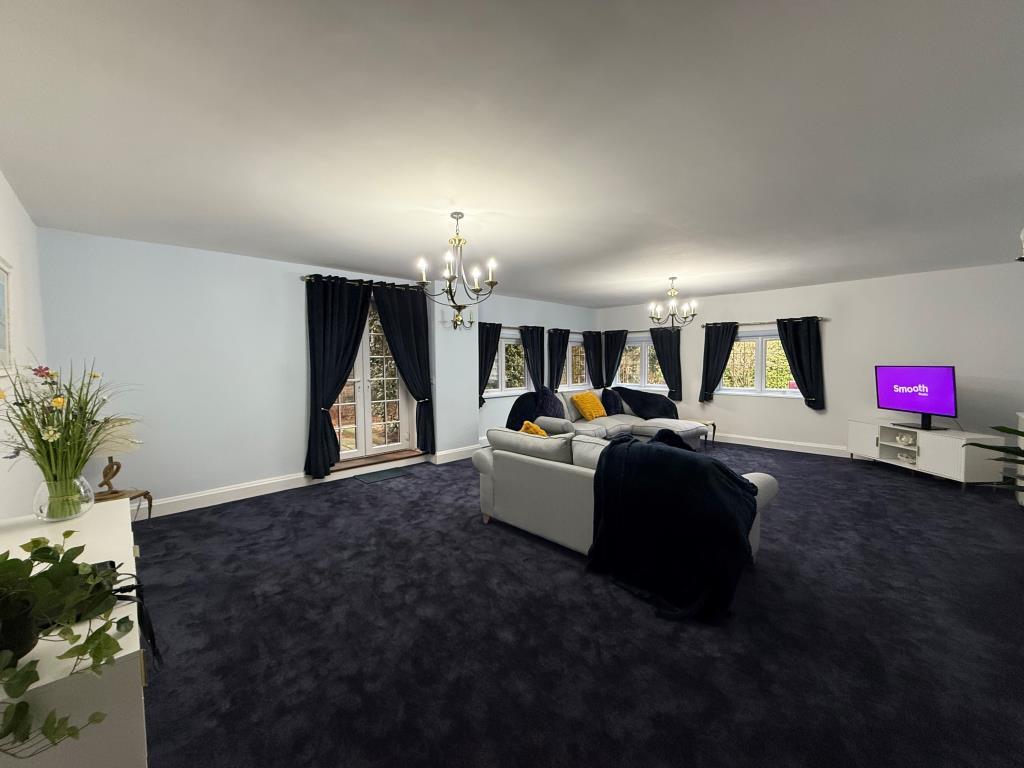 Overview shot of carpeted lounge with doors to gar