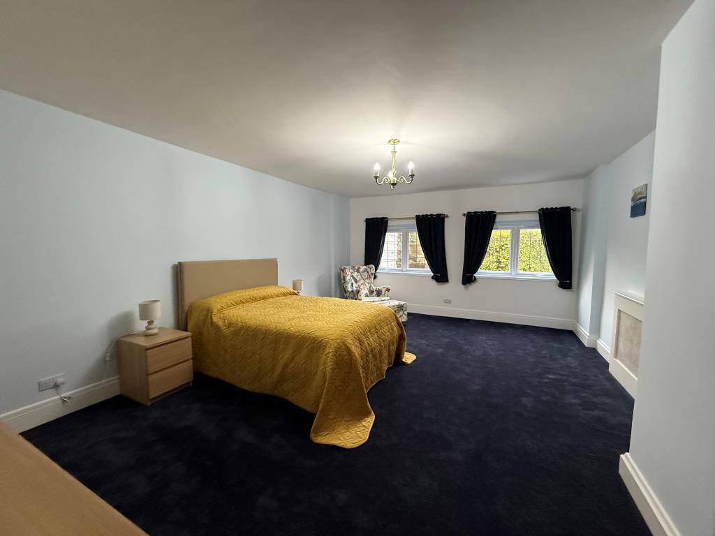 Carpeted bedroom with two windows and heaters