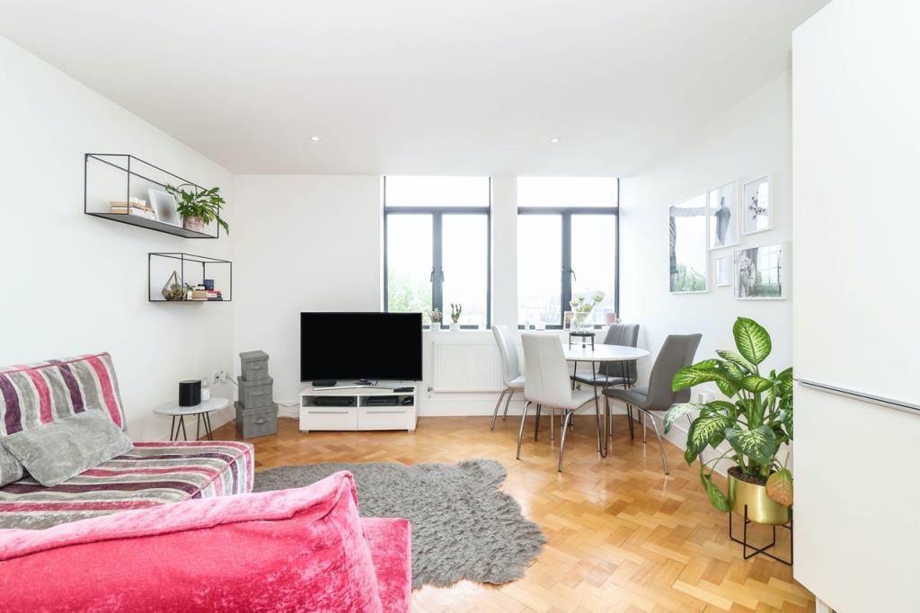 Living room with wooden floor and two windows to f
