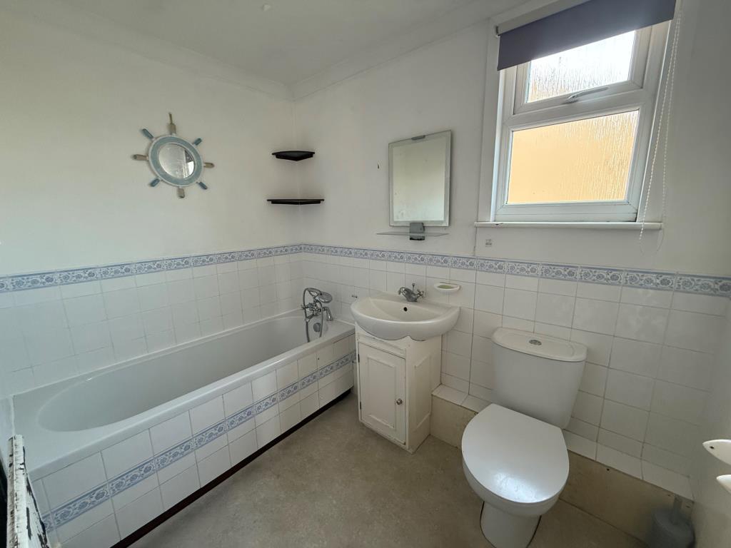 Tiled bathroom with window, bath and basin