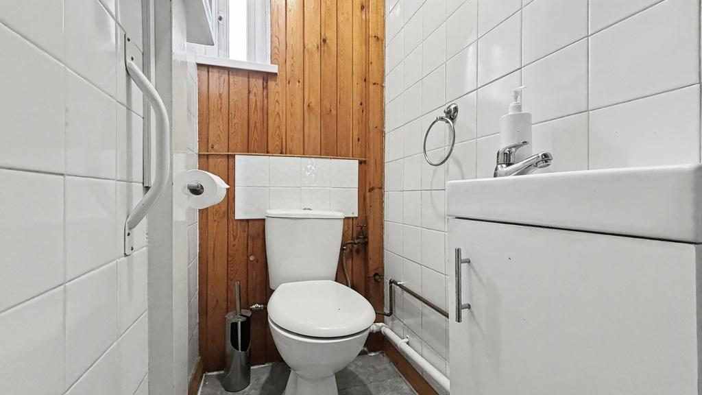 Crisp, well-maintained WC with white tiles, a c...
