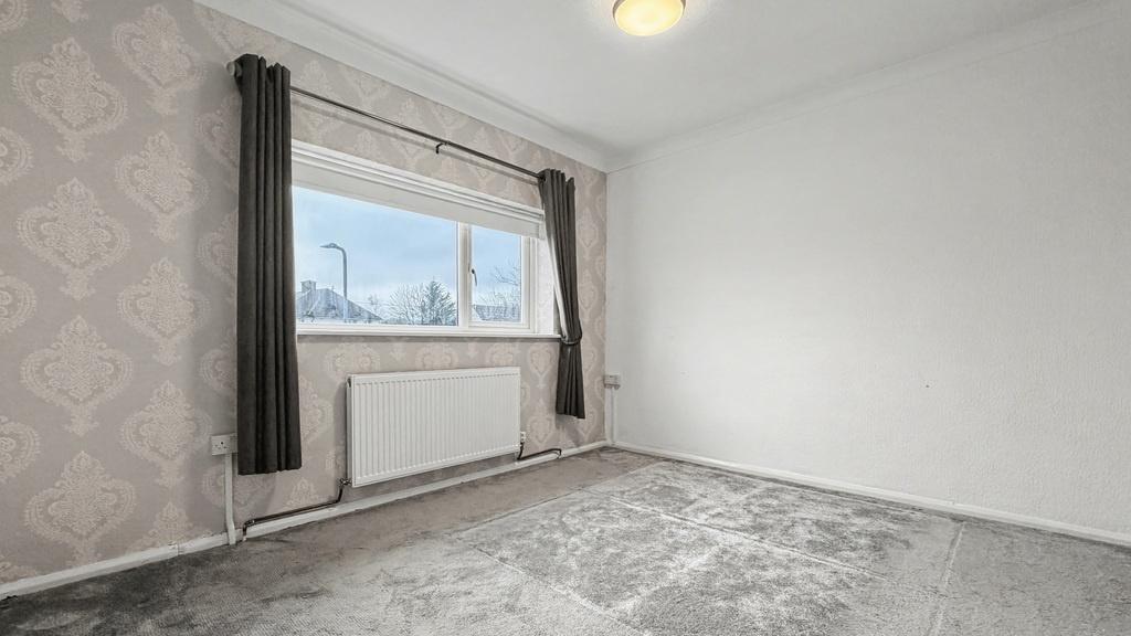 Bright double bedroom with a large window, neut...