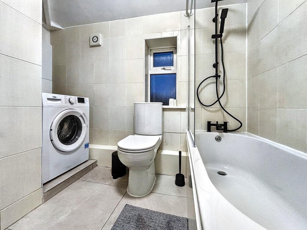 Modern tiled bathroom with a bathtub and overhe...