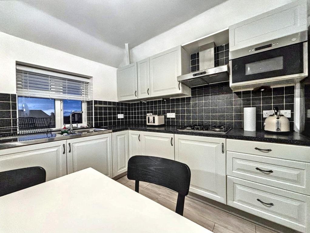 Bright, modern U-shaped kitchen with white cabi...