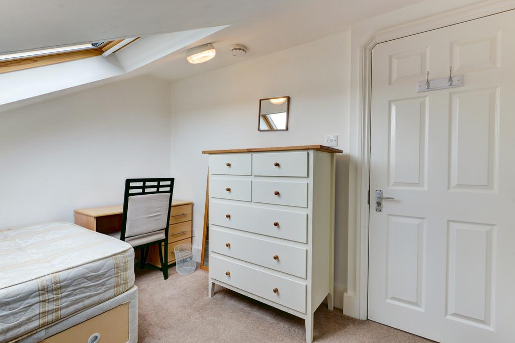 A well-lit, tidy bedroom featuring a comfortabl...