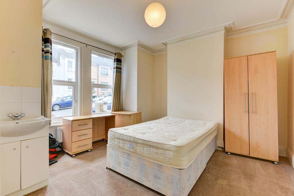 A modestly sized student bedroom with a single ...