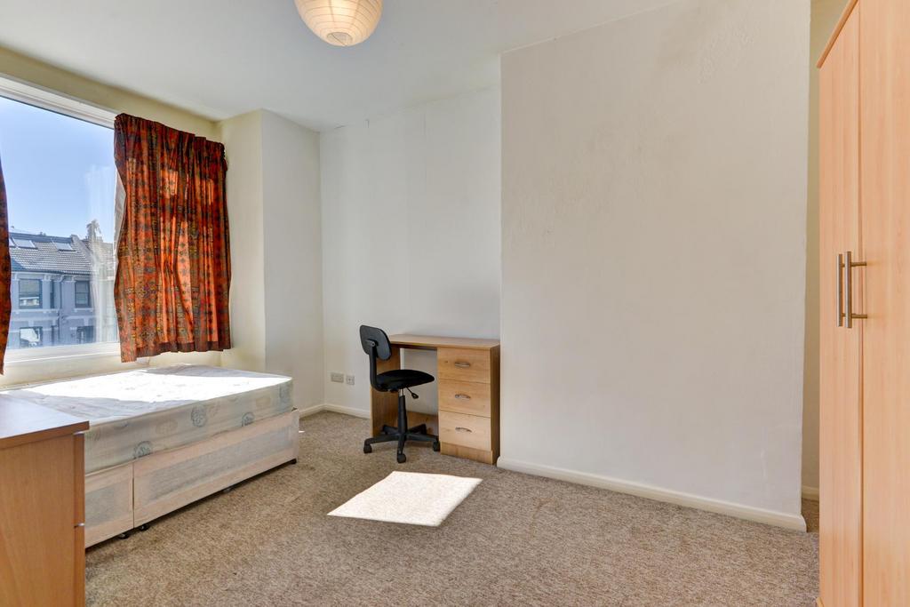 A cozy single bedroom featuring a simple bed, a...