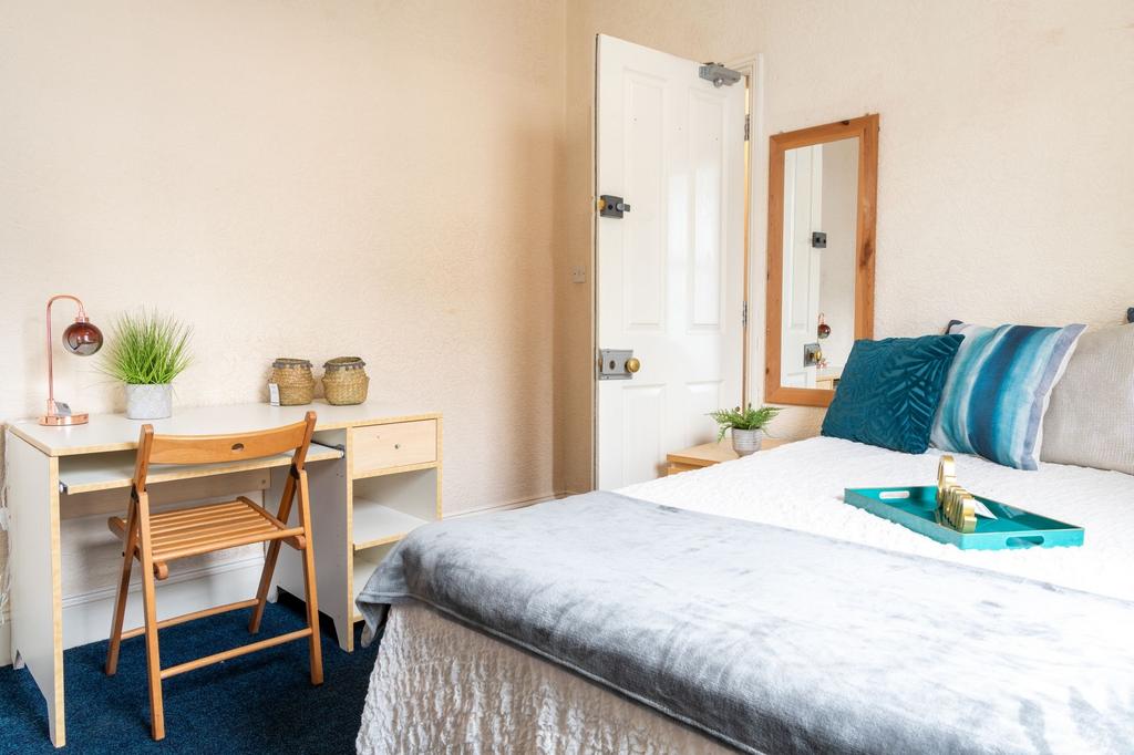 Bright, neatly styled bedroom with a comfortabl...