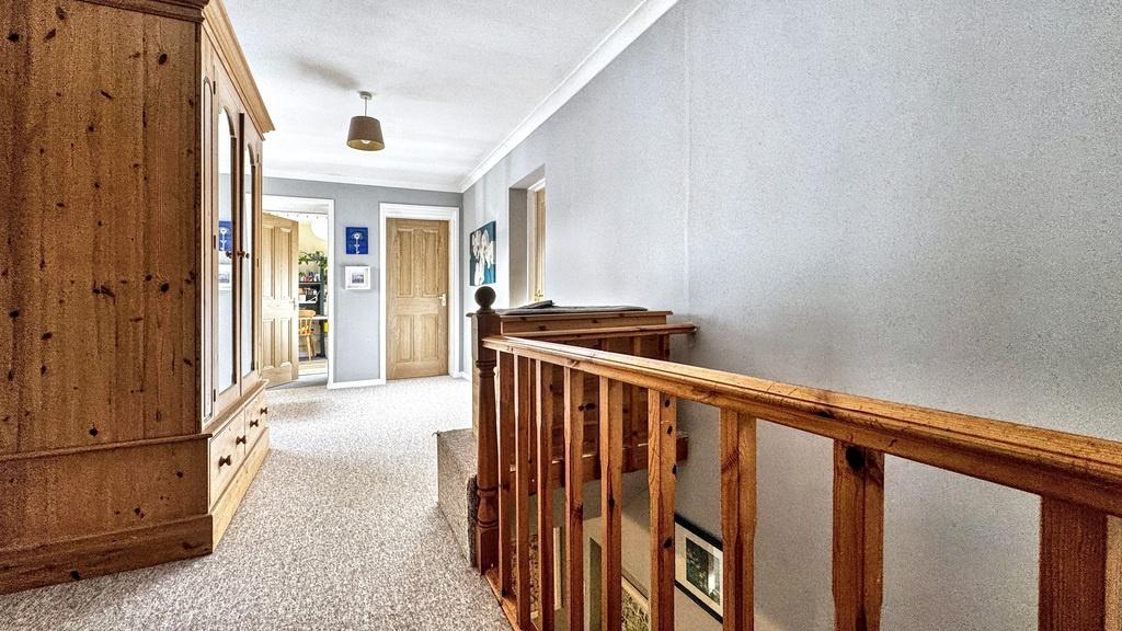 Bright carpeted upstairs hallway with natural l...