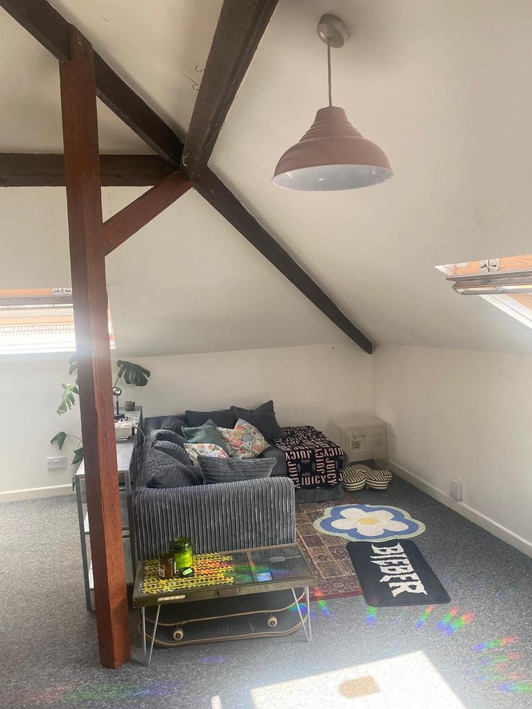Bright attic living area with exposed beams, a ...