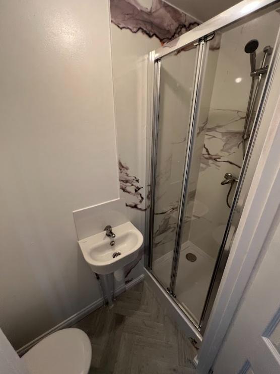 Compact modern bathroom with a glass-enclosed s...