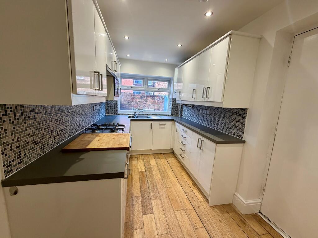 Bright modern galley kitchen with high-gloss wh...