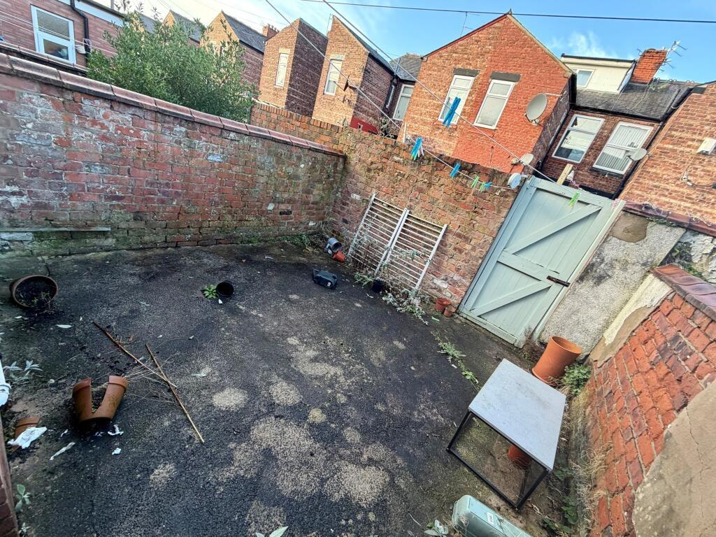 Walled rear yard with a paved surface, garden g...