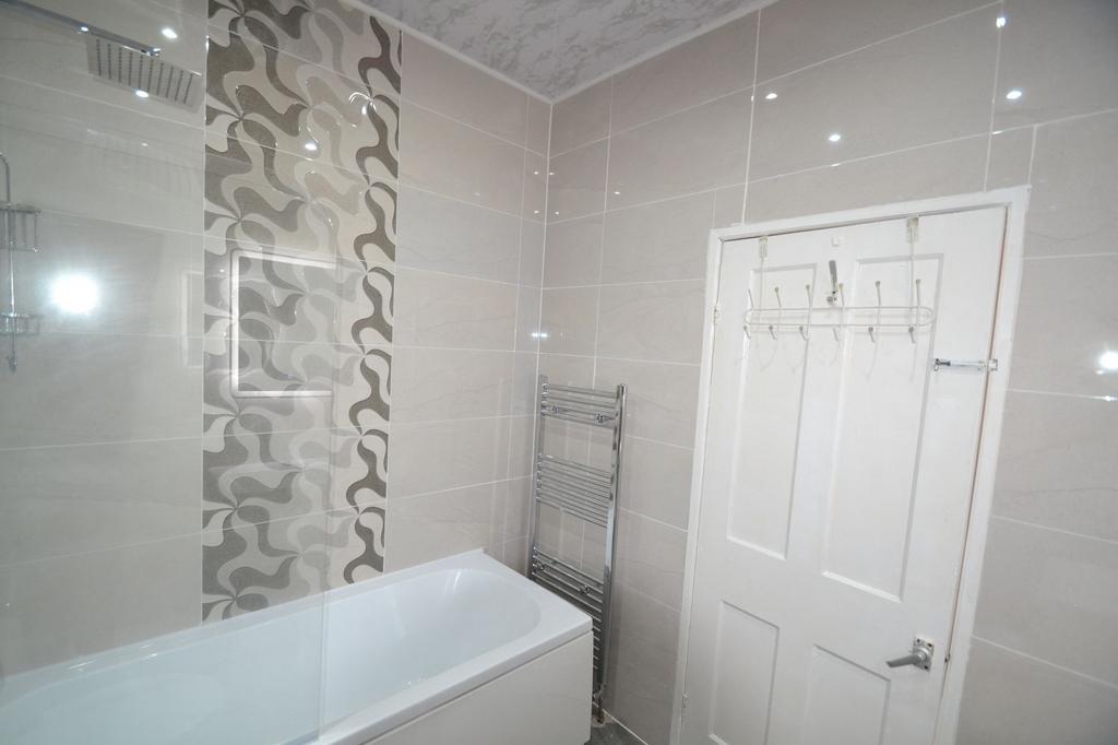Modern bathroom featuring a bathtub, tiled wall...