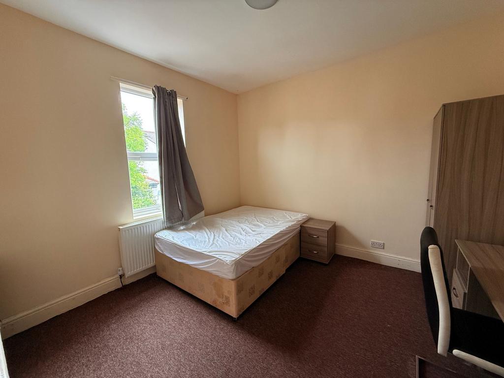 Bright, neutrally decorated bedroom with a wind...