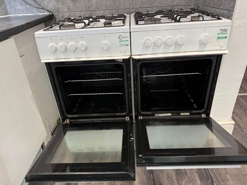Twin gas cookers with open oven doors set into ...